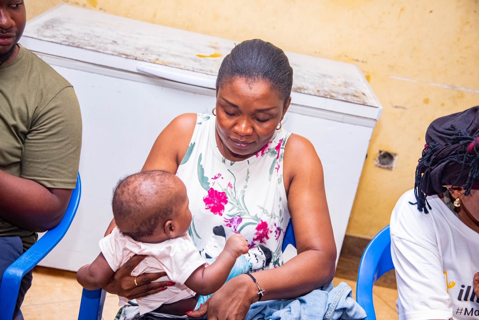 Bénévole FFOM prenant soin d'un nourrisson lors d'une action de soutien aux familles, Kinshasa, Pâques 2025